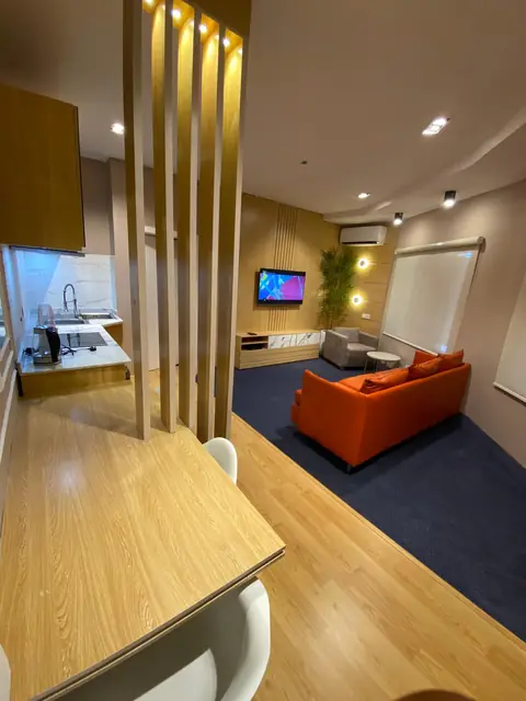 Living area with timber slats, an orange sofa and a blue rug